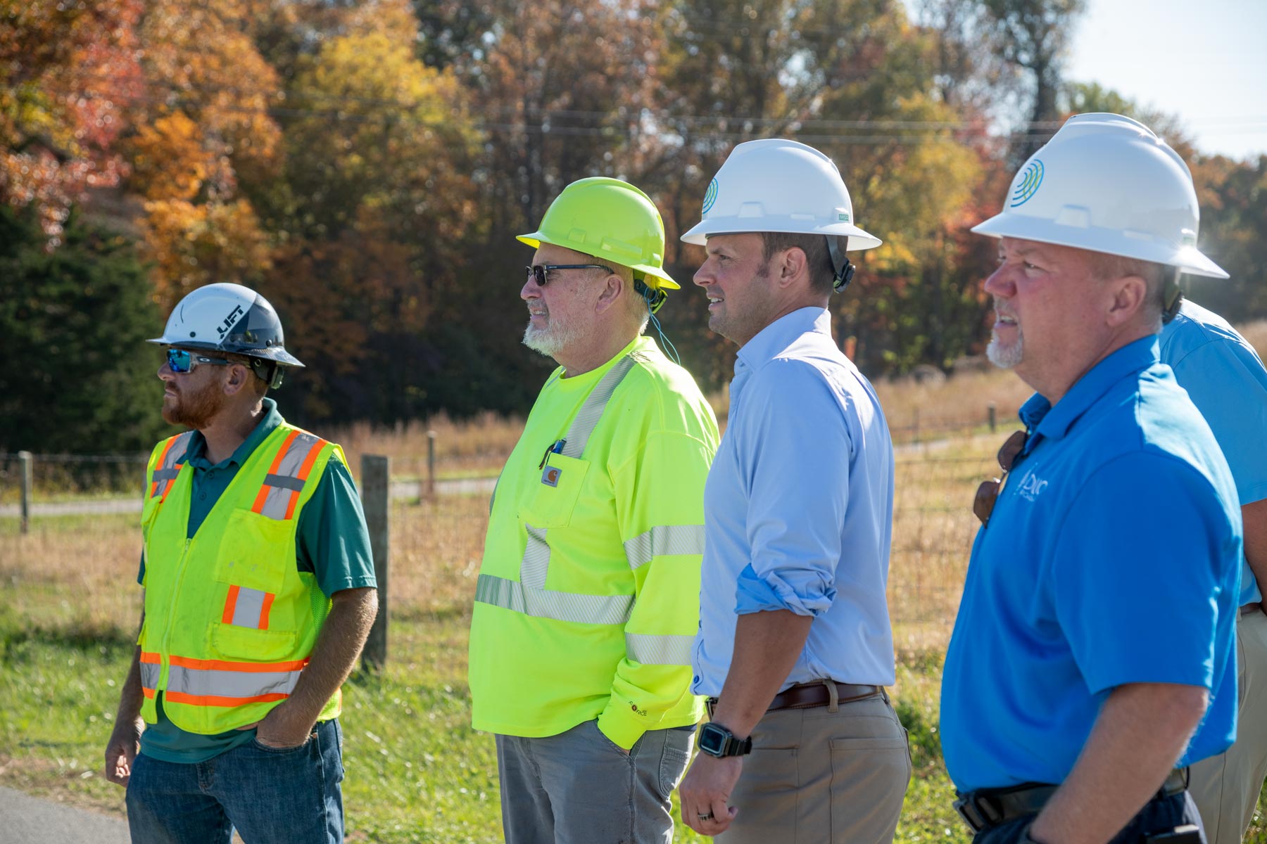 A group of 4 men in hard hats looking off at construction progress