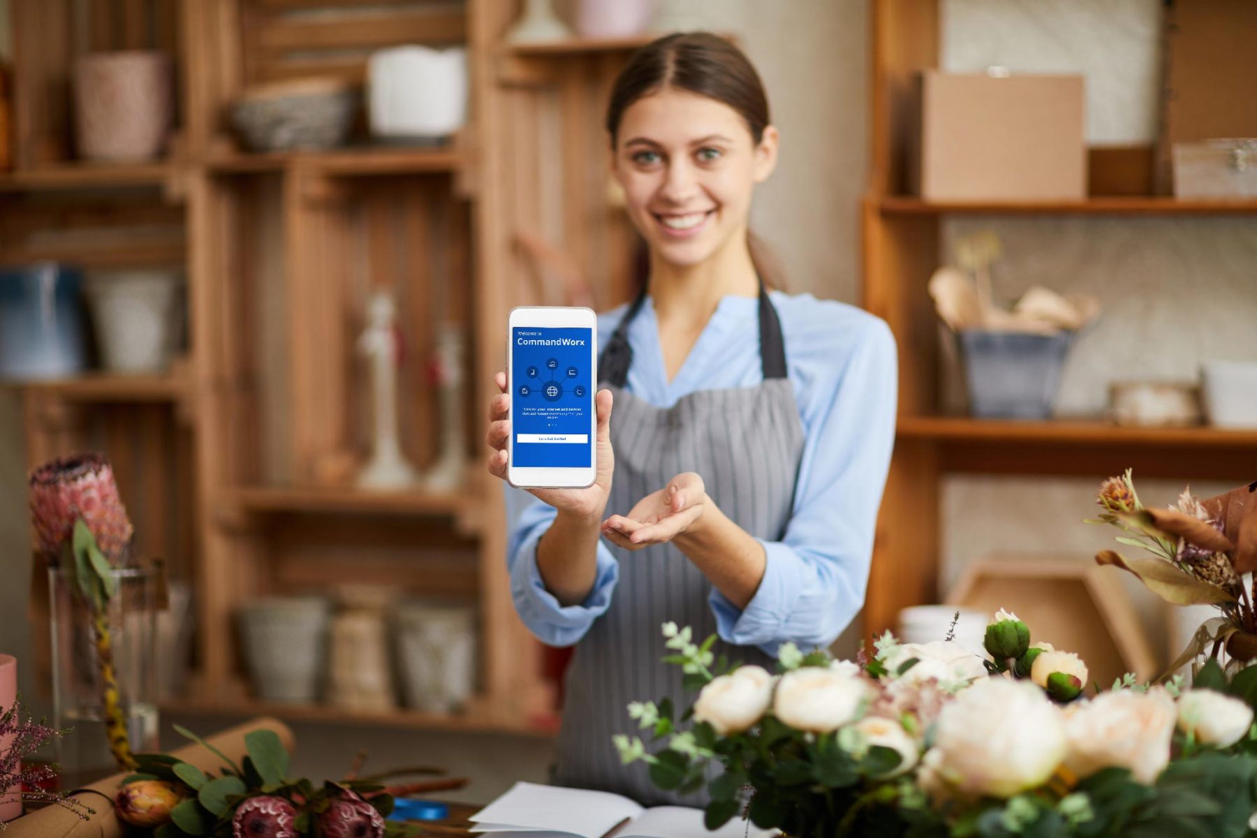 Shop keeper holding smartphone with Command Worx home screen displayed