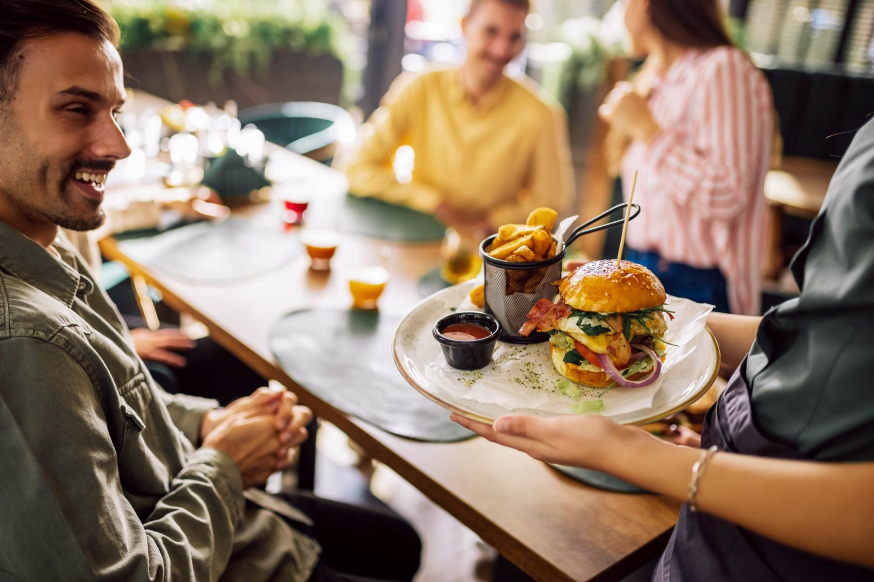 restaurant with waiter serving a burger to a table of customers