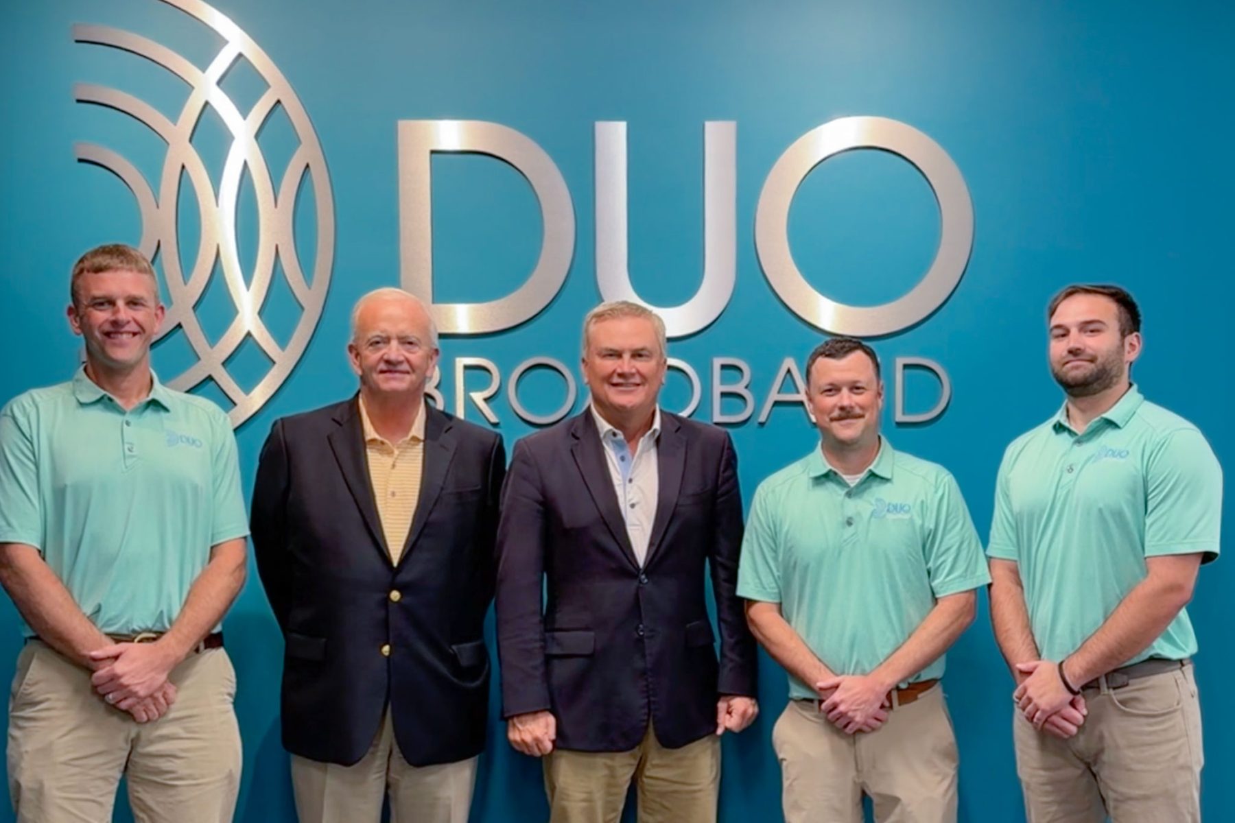 group of people in front of a DUO Broadband logo